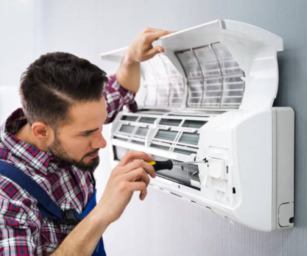 Happy Male Technician Repairing Air Conditioner With Screwdriver